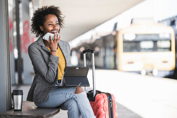 Young businesswoman using tablet and smartphone at the train station