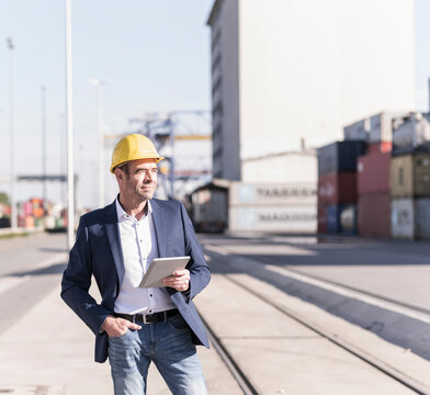 Businessman wearing safety helmet with digital tablet at industrial site