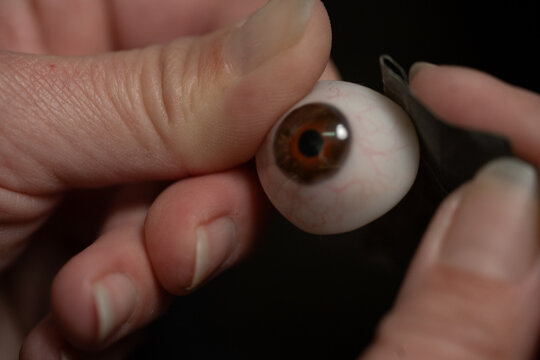 Ocularist polishing artificial eye prosthesis: close-up