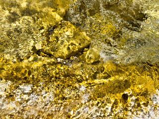 golden crystal clear river water with shimmering sunlight reflection. golden pattern. water surface. abstract natural texture. golden abstract background. warm