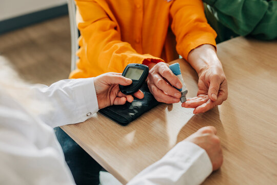 Family doctor checking blood sugar levels of an elderly woman at home