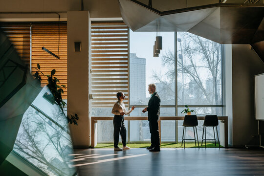 Business people having a conversation in a modern coworking space with large windows