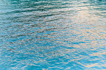 Water surface glistens with reflections under the warm glow of the setting sun in a peaceful setting.