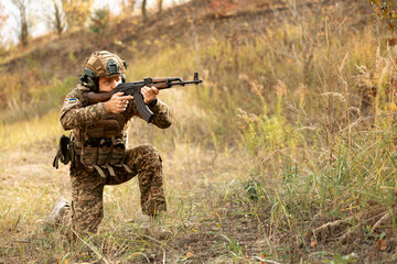 Fototapeta premium Soldier of Ukraine with assault rifle and flag of Ukraine on military uniform. Ukrainian soldier with assault rifle AK.