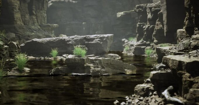 A serene river flows gently through a rugged canyon, surrounded by large stones. Soft mist hangs in the air, highlighting patches of grass growing along the waters edge.