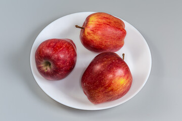 Red apples on a white dish on a gray background