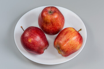 Red apples on a white dish on a gray background