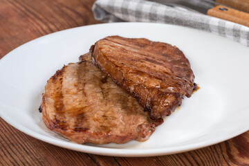 Serving of two grilled pork steaks, front view close-up