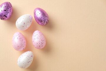 Flat lay composition with purple color Easter eggs on beige background. Easter celebration concept.