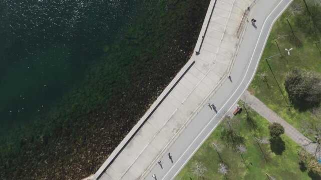 A stunning drone view of Caddebostan Coast Park on a sunny day. People enjoy the green spaces, walking paths, and seaside, while the blue waters of the Marmara Sea create a relaxing coastal atmosphere
