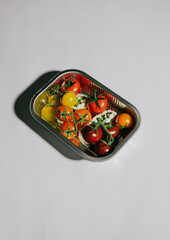 A tray of assorted tomatoes and other vegetables. The tray is silver and the vegetables are red and green