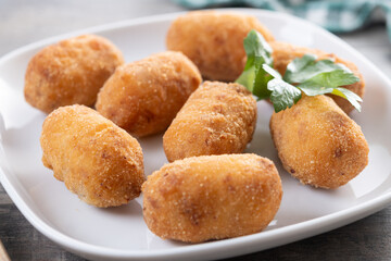 Fried cod croquettes on wooden table. Close up