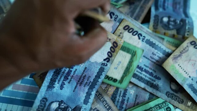 Counting bangladeshi Taka Banknotes, A hand counting a pile of bangladeshi Taka banknotes of various denominations