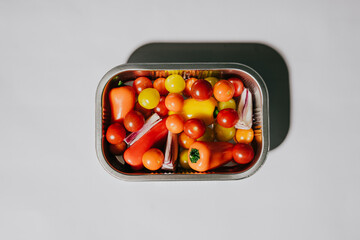 A silver tray with a variety of vegetables including tomatoes, peppers, and onions. The tray is placed on a white background