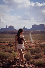 Attractive young woman sightseeing on the road against the backdrop of Monument Valley, on the west coast of the United States.