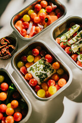 A variety of fruits and vegetables are displayed in metal containers. The containers are arranged in a way that highlights the colors and textures of the food. Scene is healthy and inviting