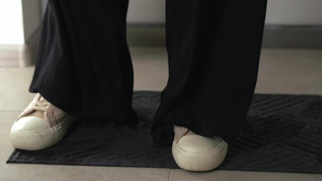 A man stands on a doormat at the entrance to an apartment.
Wipe dirty shoes after being outside.
A man in dirty sneakers.
Close-up of dirty sneakers on a doormat