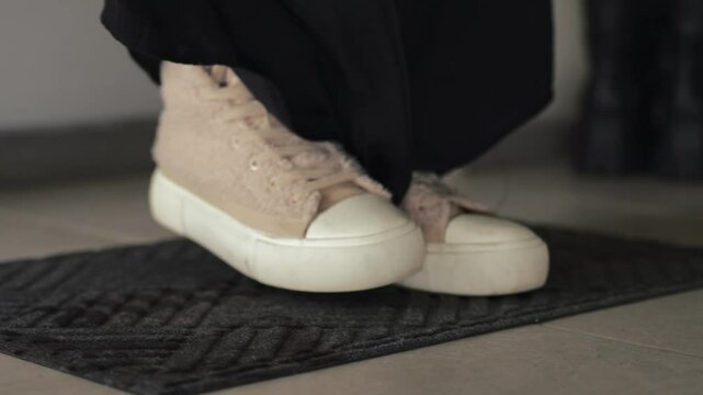 A man stands on a doormat at the entrance to an apartment.
Wipe dirty shoes after being outside.
A man in dirty sneakers.
Close-up of dirty sneakers on a doormat