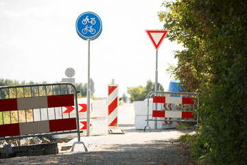 Bicycle path obstruction with construction barriers and yield sign in a sunny outdoor setting near...