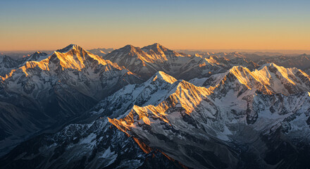 Aerial View of Snow Capped Mountains Illuminated by Golden Sunlight at Sunrise or Sunset