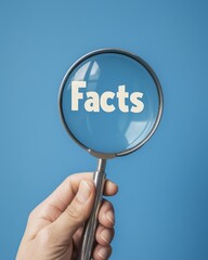 A hand holding a magnifying glass focuses on text showing "Facts" on a blue background 