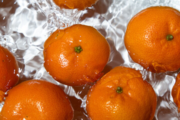 Fresh tangerines splashing into clear water top view