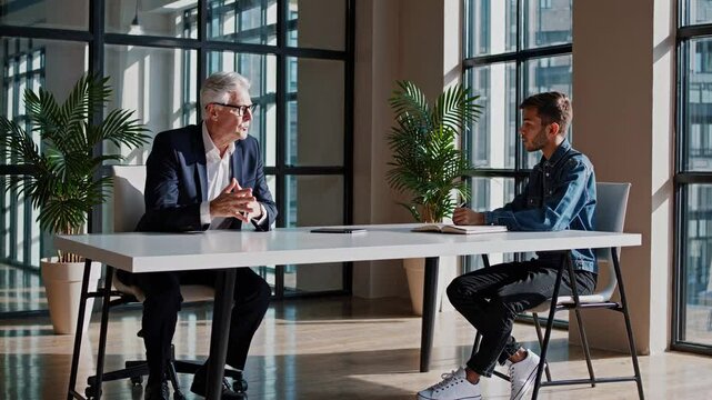 Two individuals engage in a meaningful discussion about career paths and personal growth in a bright, contemporary office with large windows