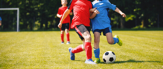 Happy kids compete in football game. Young boys playing soccer game. Kids having fun in sport. Running soccer players. Competition between players running and kicking football ball. Football school