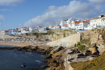 Scenic view of Ericeira beach with cliffs, rocks, and soft sand, overlooking traditional white...