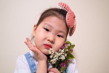 A young girl wearing a pink flower headband holding a bouquet of flowers