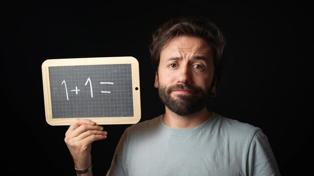 Caucasian Man holding a Chalkboard with the Handwritten word  "1+1="