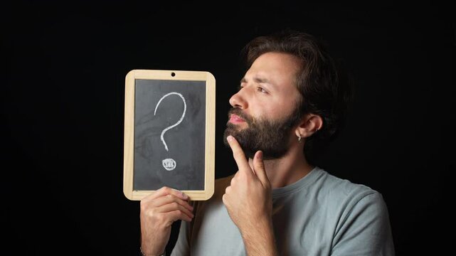 Person holding a blackboard with a white question mark against a black background.