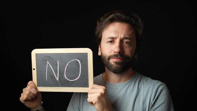 Caucasian Man holding a Chalkboard with the Handwritten word  "no" 
