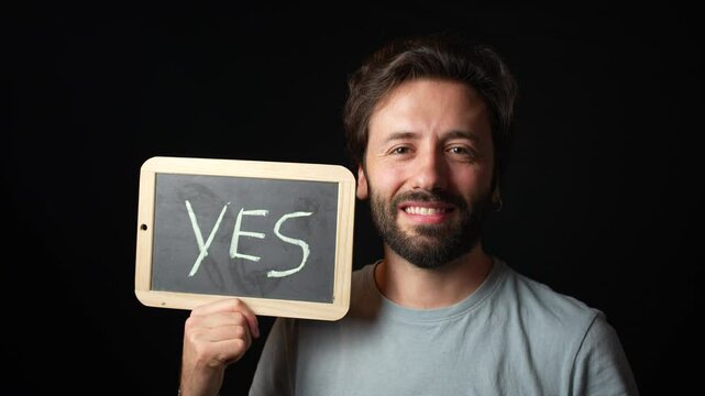 Happy caucasian Man holding a Chalkboard with the Handwritten word  "yes"