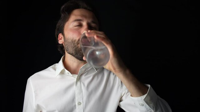 Person wearing a shirt drinking water against a black background.