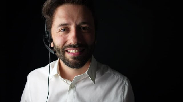 Happy call center operator wearing a headset, smiling and looking directly at the camera.