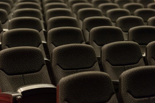 Rows of empty black convention center seats with dim lighting