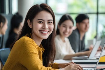A group of professionals work together in a bright office with large windows. A young woman smiles as she types on her laptop, showcasing a collaborative atmosphere.