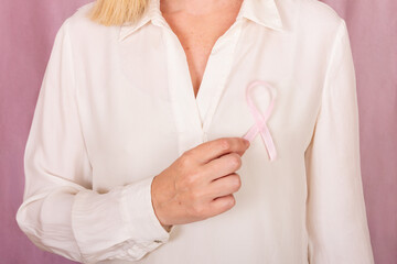 Woman holding pink ribbon for breast cancer awareness