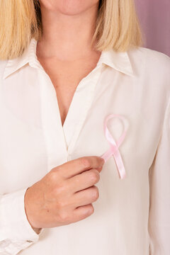 Woman holding pink ribbon symbolizing cancer awareness