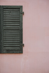 Closed Green Shutter on Pink Wall