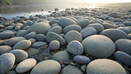 Obraz premium A beach covered with smooth, rounded stones, showcasing natural rock formations. 