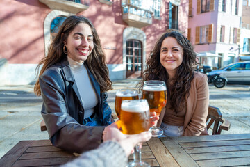 Hispanic women toasting with beer at bar terrace - Group of Hispanic women enjoying drinks and toasting with beer at a sunny bar terrace - Beverage concept with friends