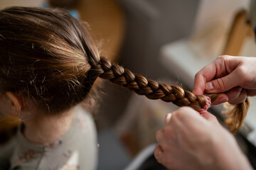 Mom making daughters hair in the morning close up before going to kindergarten