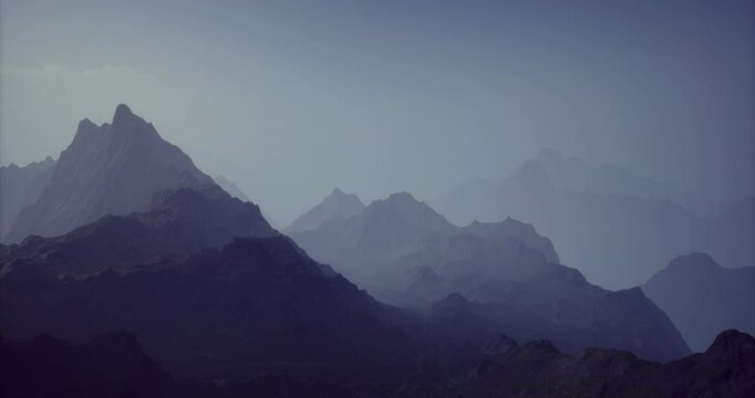 A vast mountain landscape displays a range of peaks fading into the distance. Soft light casts a mysterious atmosphere over the rugged terrain during twilight hours.