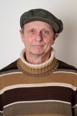 Senior man with a beige turtleneck puulover and a vintage cap