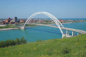 Obraz premium View of modern bridge spanning turquoise waters with city skyline in background on a clear sunny day