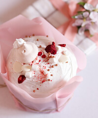 Easter cake with white icing and strawberry pieces in a pink wrapper with a blossoming apple branch. Happy Easter. Space for text, Easter card, greetings, greeting card, religious Easter, business