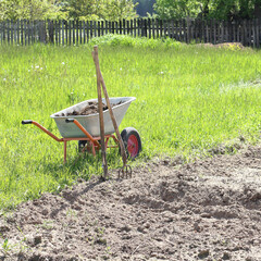 wheelbarrow with compost near a plowed field. fertilizer for planting