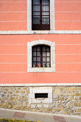 Ventanas en fachada antigua pintada de rosa con líneas blancas